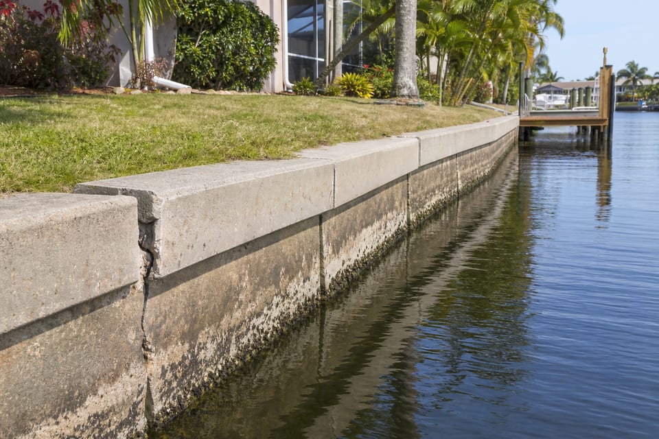 Illustration of an aged concrete seawall with a localized crack along a longer wall section.