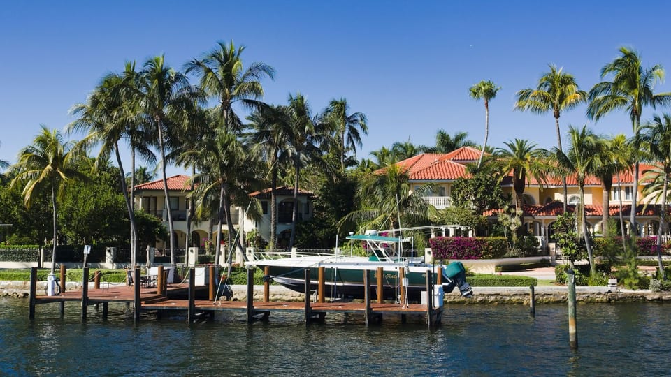 Waterfront homes with palm trees, docks, and a boat along a Florida waterway
