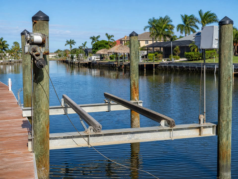 Illustration of an empty boat lift with corroded hardware, uneven bunks, and a slack cable beside a canal.