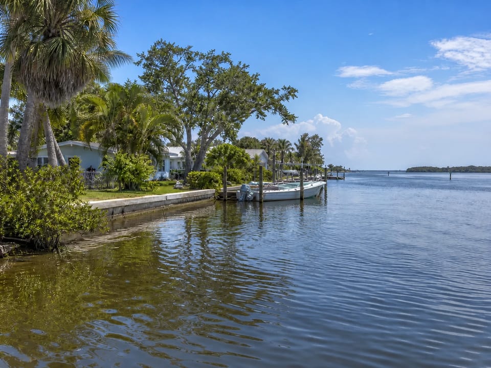 Illustration of waterfront homes and docks with a center-console boat in a residential channel.