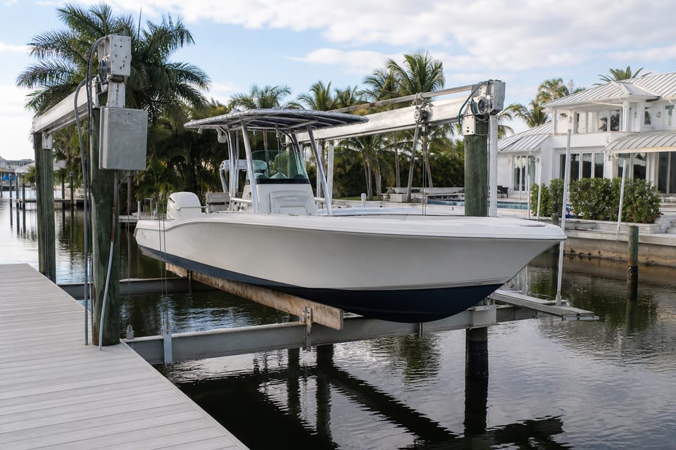 Illustration of a residential boat lift holding a center-console boat beside a canal.